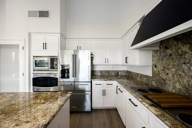 a kitchen with granite countertop a refrigerator stove and oven