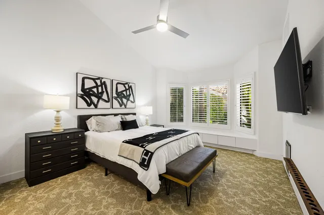 a bedroom with a bed and a flat tv screen on dresser