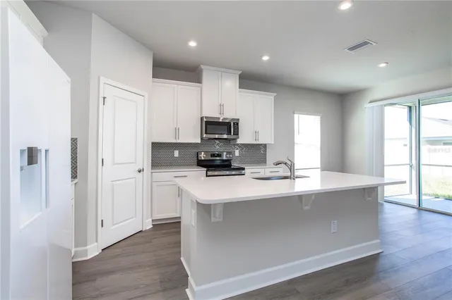 a large kitchen with stainless steel appliances granite countertop a stove a sink and a refrigerator