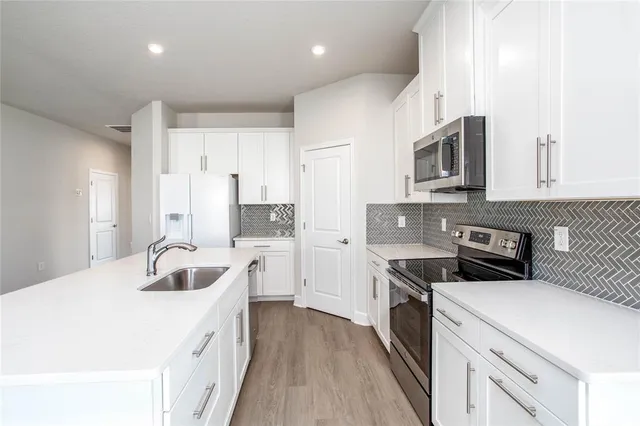 a kitchen with stainless steel appliances granite countertop a sink stove microwave and refrigerator