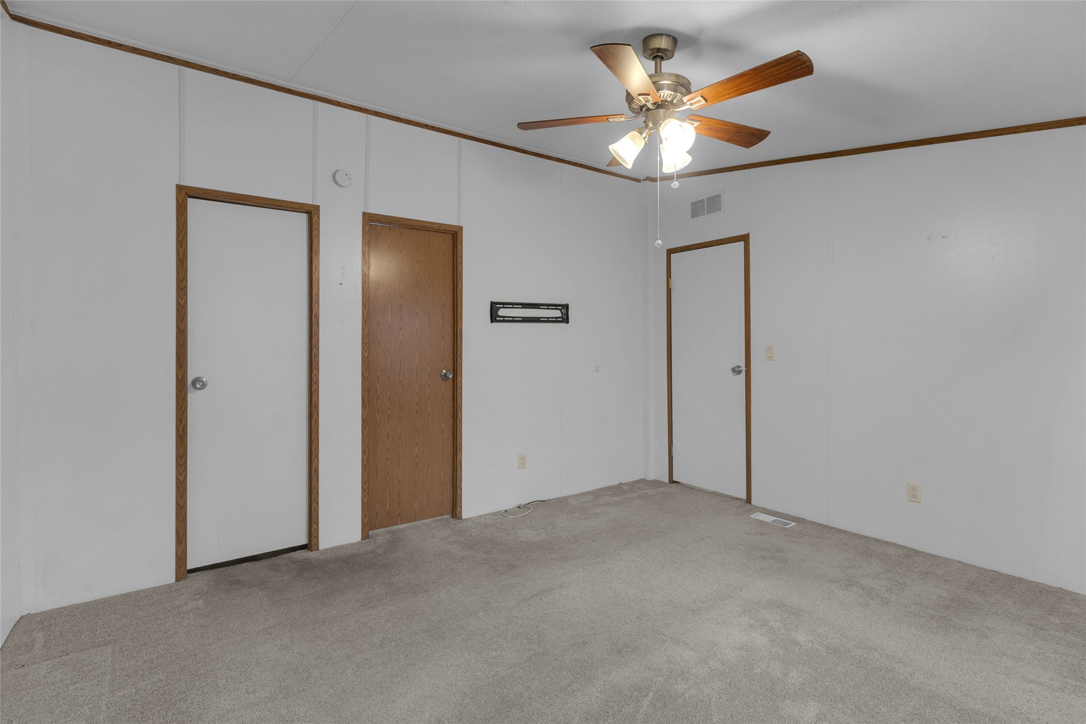 22094 Spear Road Porter, TX 77365 - Photo 22 of 45 This room features neutral carpet and walls, a ceiling fan with lights, and three wooden doors, offering a versatile space for customization.