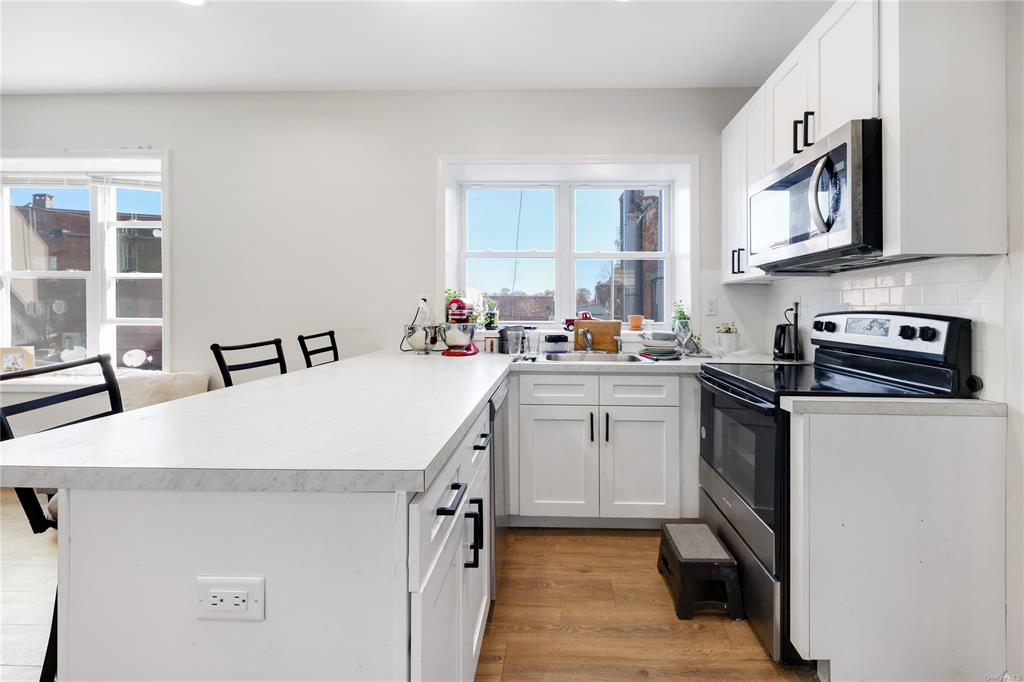 5-13 Academy Street Poughkeepsie, NY 12601 - Photo 5 of 11 Kitchen featuring kitchen peninsula, appliances with stainless steel finishes, a breakfast bar, and white cabinets