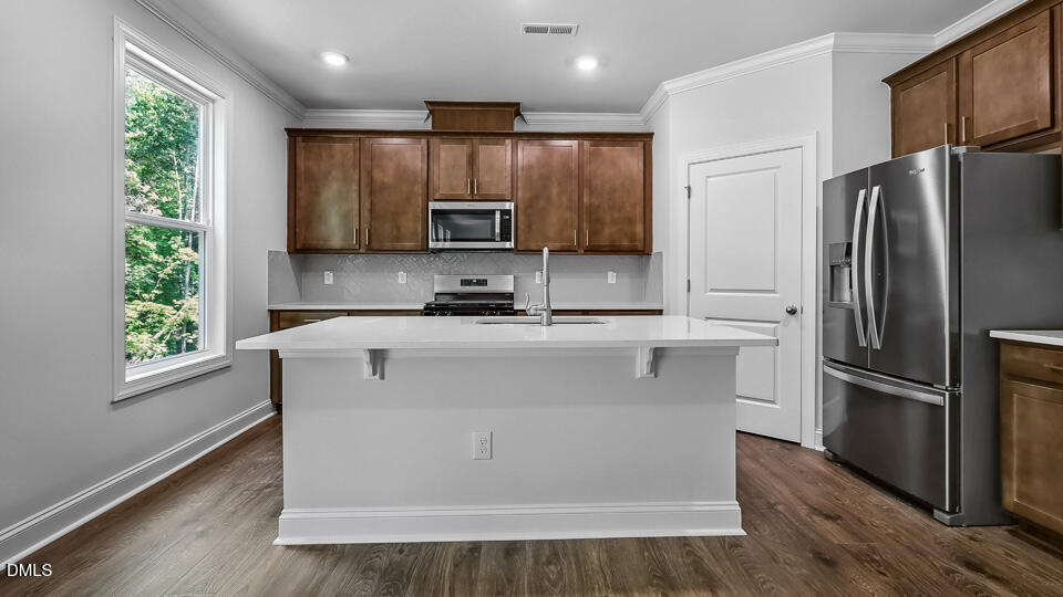 7589 Percussion Drive Apex, NC 27539 - Photo 11 of 33 a kitchen with kitchen island a refrigerator and a stove top oven