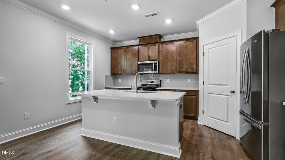 7589 Percussion Drive Apex, NC 27539 - Photo 12 of 33 a kitchen with stainless steel appliances granite countertop a refrigerator a sink a stove a microwave and wooden floor