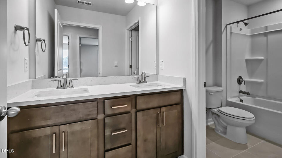 7589 Percussion Drive Apex, NC 27539 - Photo 25 of 33 a bathroom with a double vanity sink toilet and shower