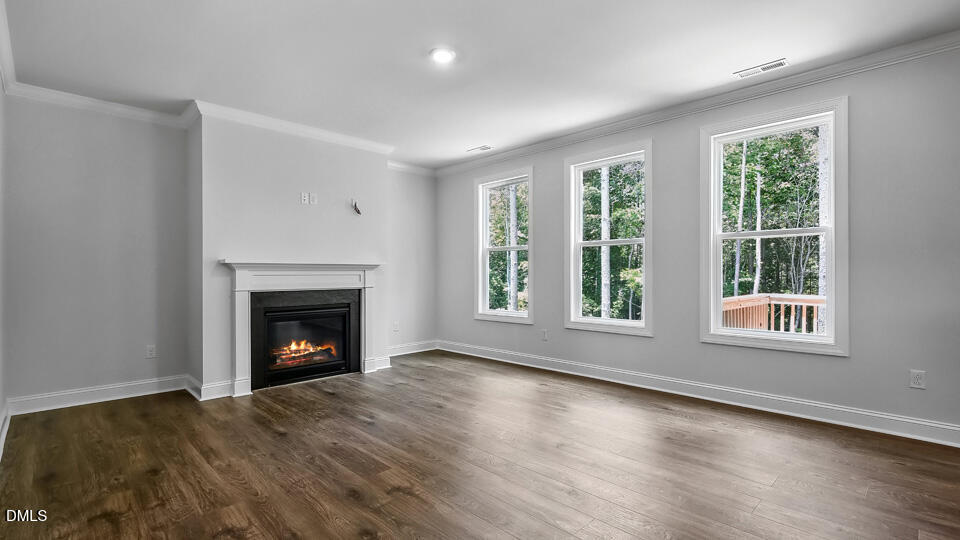 7589 Percussion Drive Apex, NC 27539 - Photo 3 of 33 an empty room with wooden floor fireplace and windows