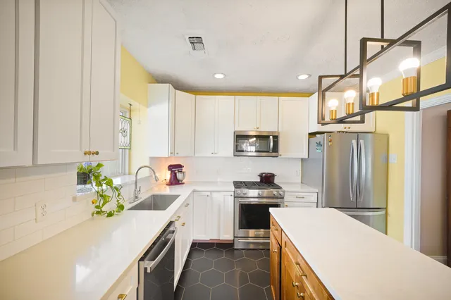 a kitchen with stainless steel appliances a sink a counter top space cabinets and a wooden floor