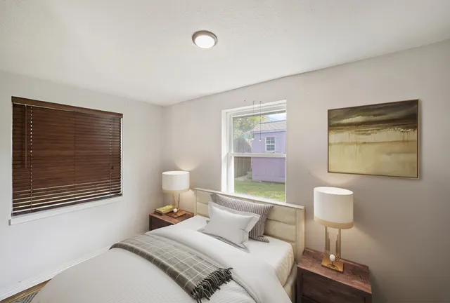 a bedroom with a bed and a lamp on dresser