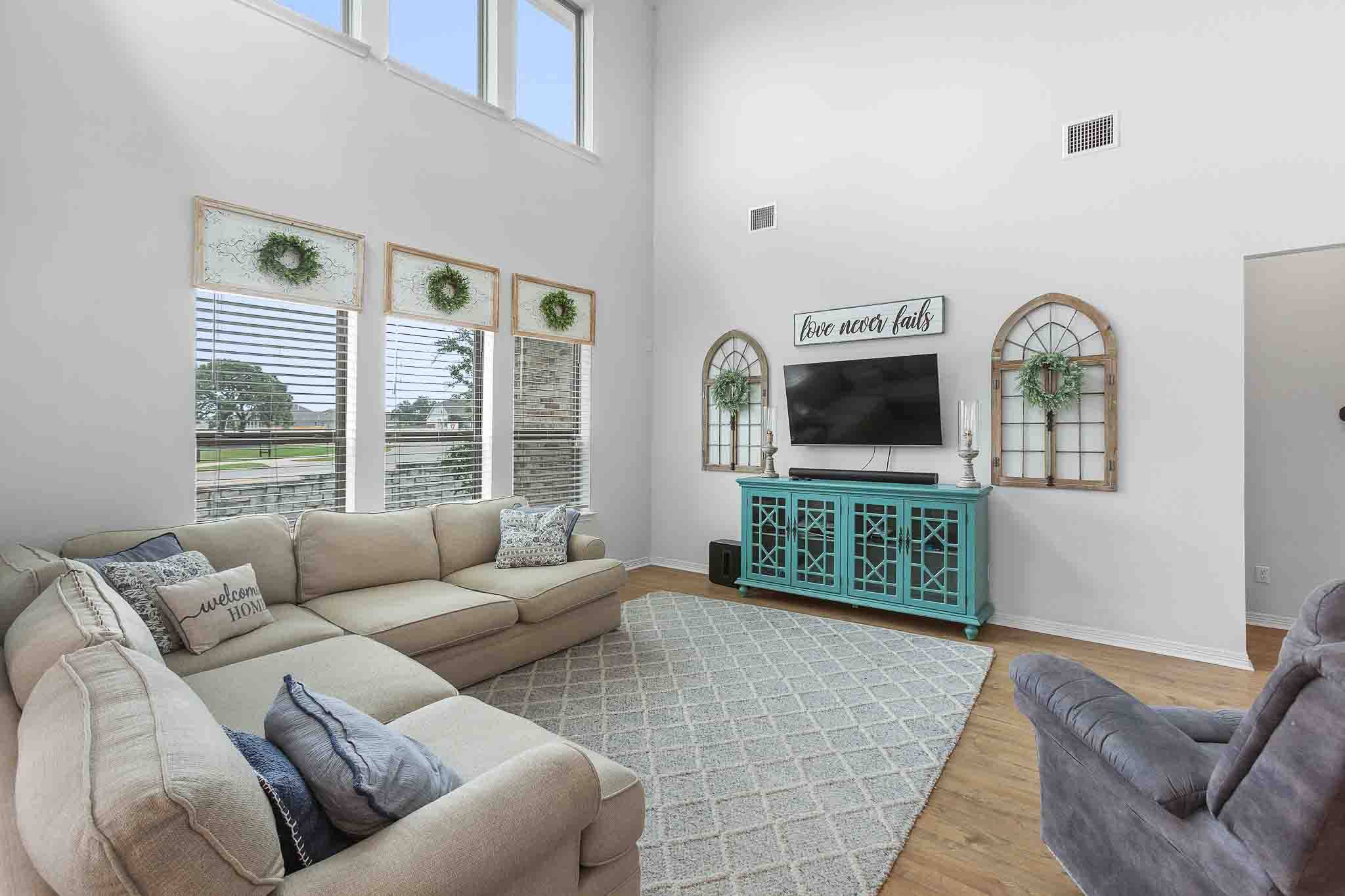 166 West Branch Road Kyle, TX 78640 - Photo 12 of 39 Natural light floods this living area through a wall of windows, highlighting the high ceilings and elegant flooring.