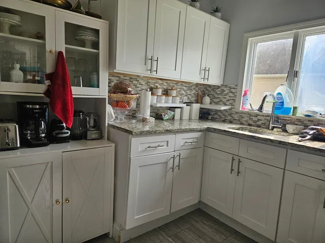 a kitchen with white cabinets and sink