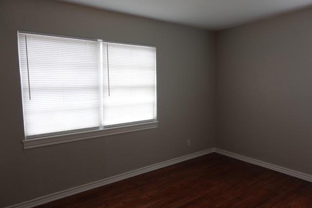8706 Cardella Avenue Dallas, TX 75217 - Photo 6 of 8 a view of an empty room with wooden floor and a window