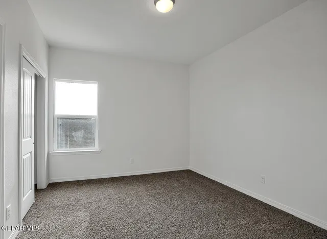 a view of an empty room with closet and a window