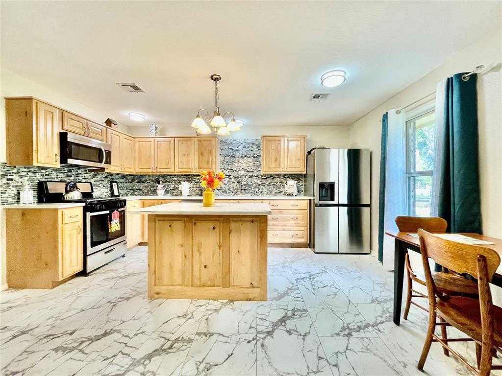 945 Brickyard Road West, TX 76691 - Photo 8 of 25 a kitchen with stainless steel appliances kitchen island granite countertop a refrigerator a stove a sink dishwasher and white cabinets with wooden floor