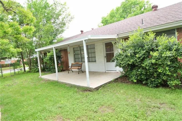 a view of backyard with table and chairs potted plants and large tree