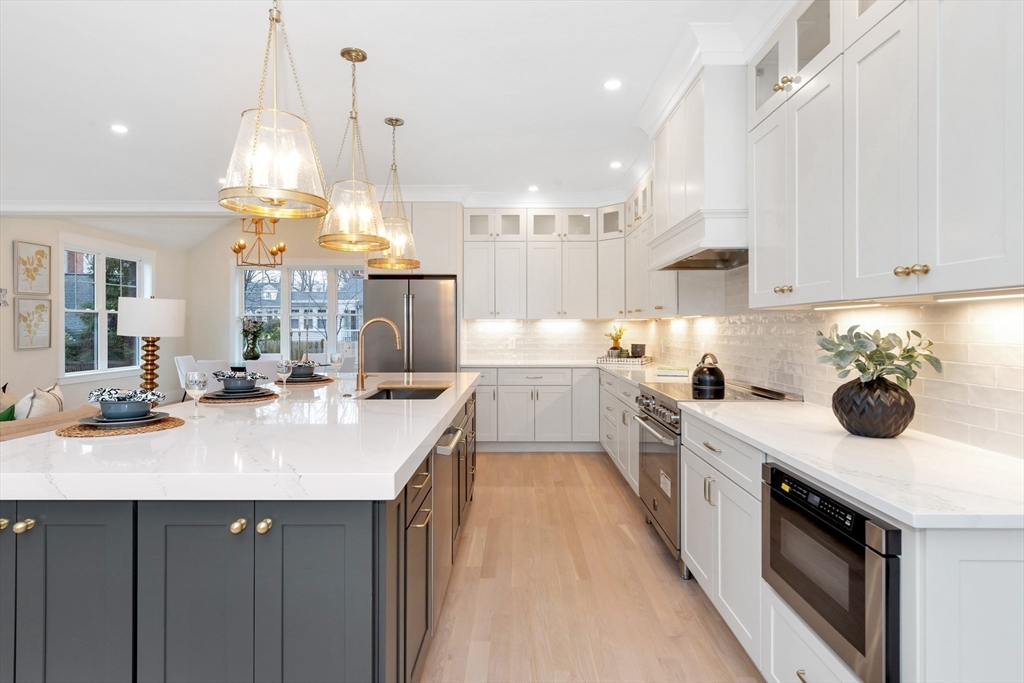 19 Cherokee Road Arlington, MA 02474 - Photo 5 of 42 a kitchen with a sink dishwasher a stove and a dining table with wooden floor