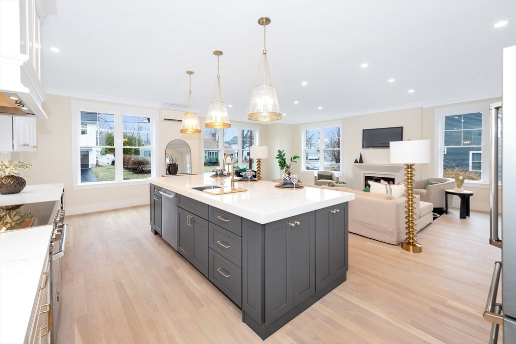 19 Cherokee Road Arlington, MA 02474 - Photo 7 of 42 a large white kitchen with a large island oven a sink dishwasher and a stove with wooden floor
