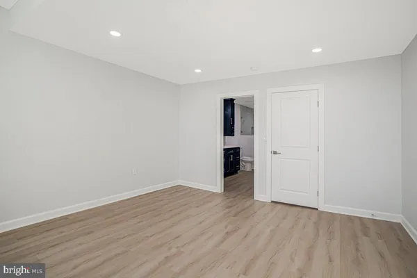 a view of an empty room with wooden floor and closet