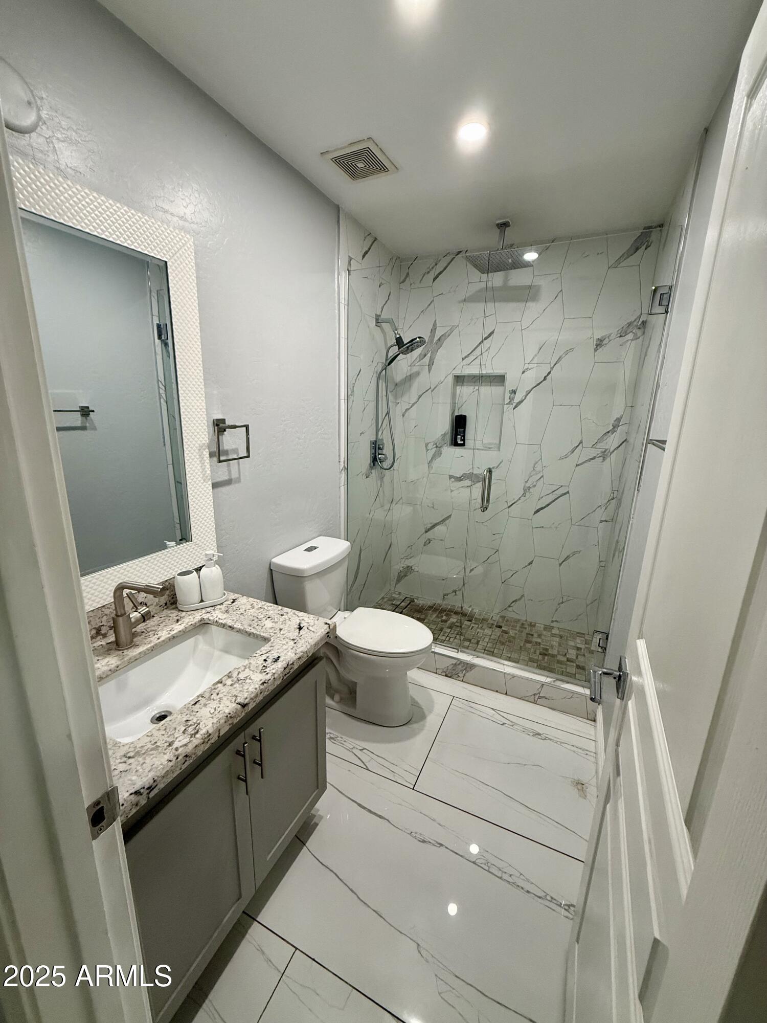 8534 West Cordes Road Tolleson, AZ 85353 - Photo 12 of 22 a bathroom with a granite countertop sink a toilet a mirror and shower