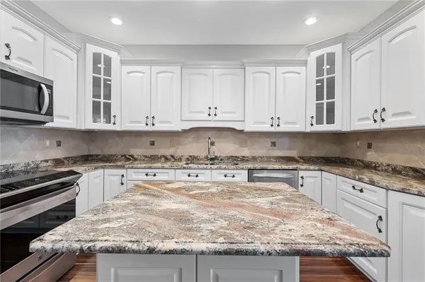 a kitchen with granite countertop white cabinets and stainless steel appliances