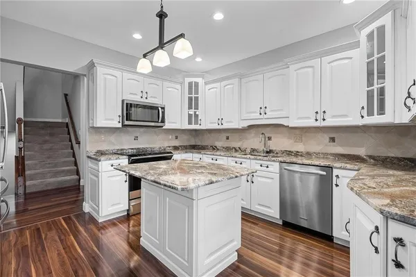 a kitchen with granite countertop cabinets stainless steel appliances and a wooden floor