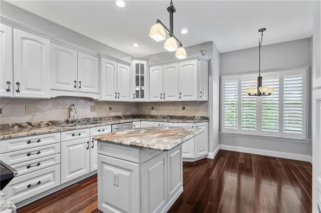a kitchen with stainless steel appliances granite countertop hardwood floor sink stove and white cabinets