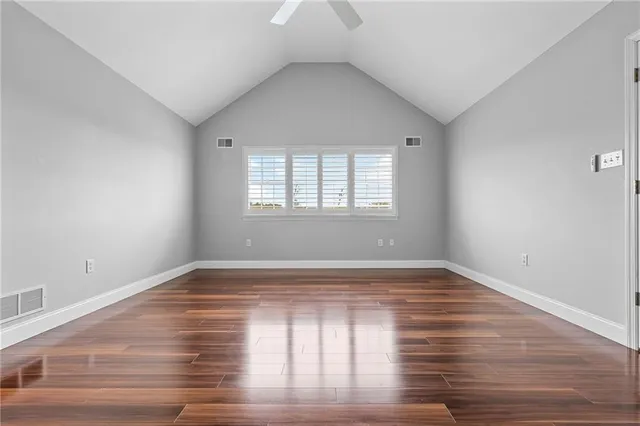 a view of an empty room with wooden floor and window