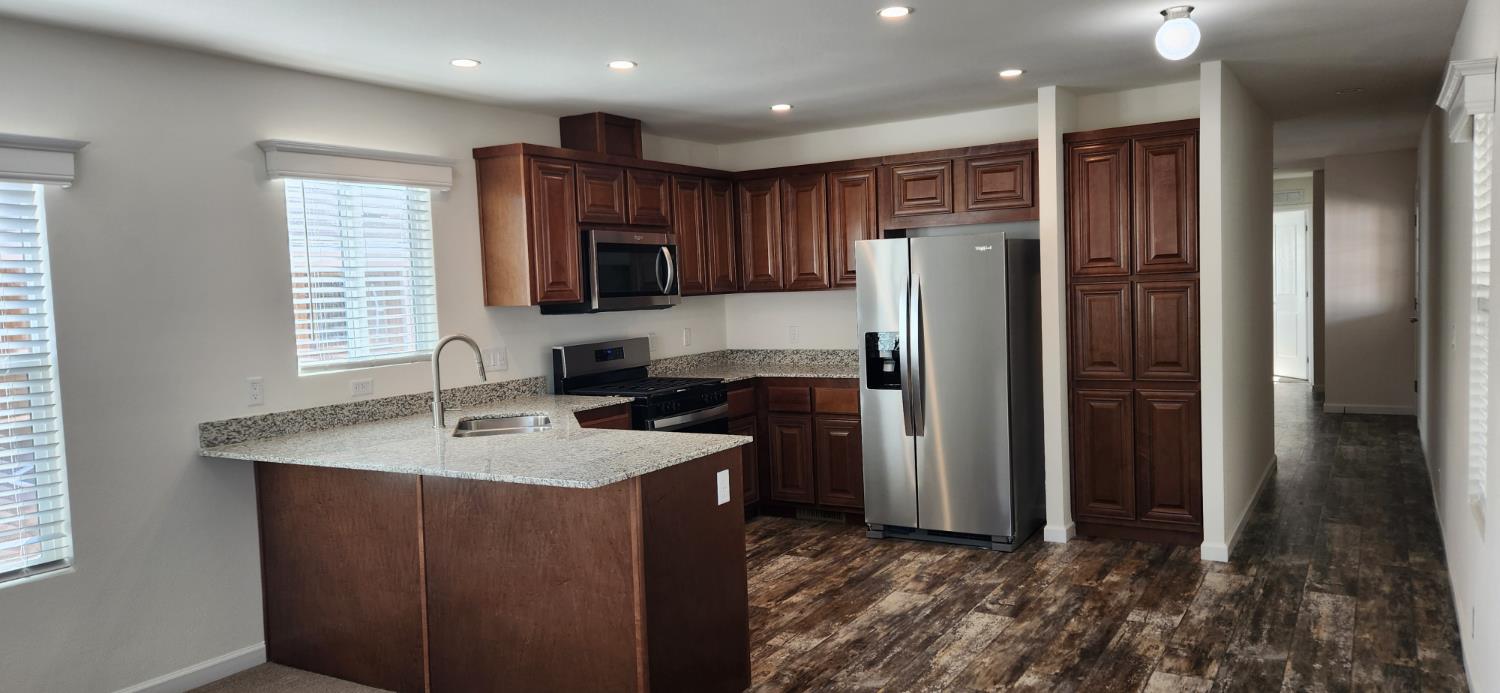 350 Pleasant Valley Road, Unit 56 Diamond Springs, CA 95619 - Photo 13 of 15 a kitchen with kitchen island granite countertop stainless steel appliances a refrigerator and a sink
