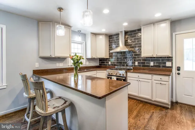 a kitchen with stainless steel appliances granite countertop a stove top oven a sink dishwasher a dining table and chairs with wooden floor