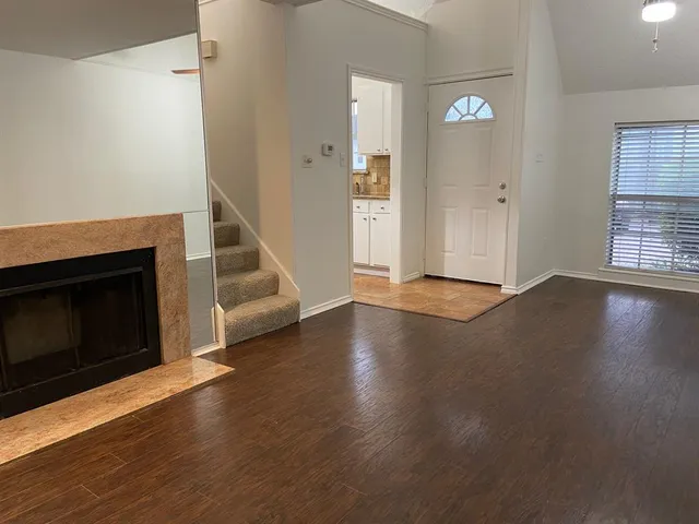an empty room with wooden floor fireplace and windows