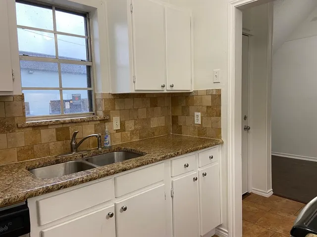 a kitchen with granite countertop a sink and cabinets