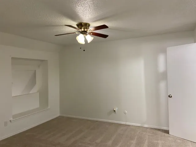 an empty room with a chandelier fan and windows