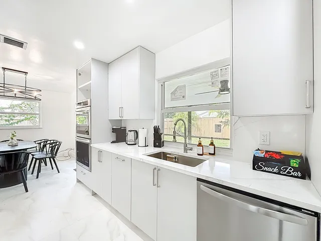 a kitchen with a sink dishwasher a dining table and chairs with wooden floor