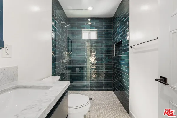 a bathroom with a granite countertop toilet a sink and shower
