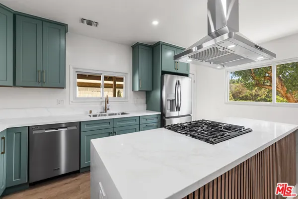 a kitchen with stainless steel appliances a refrigerator a sink dishwasher and wooden cabinets with wooden floor