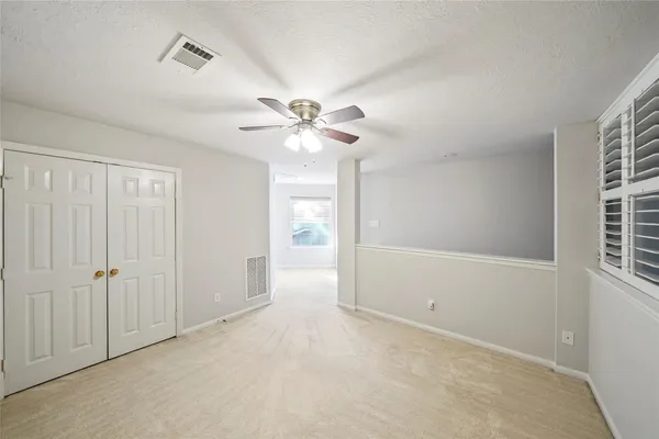 an empty room with windows and fan