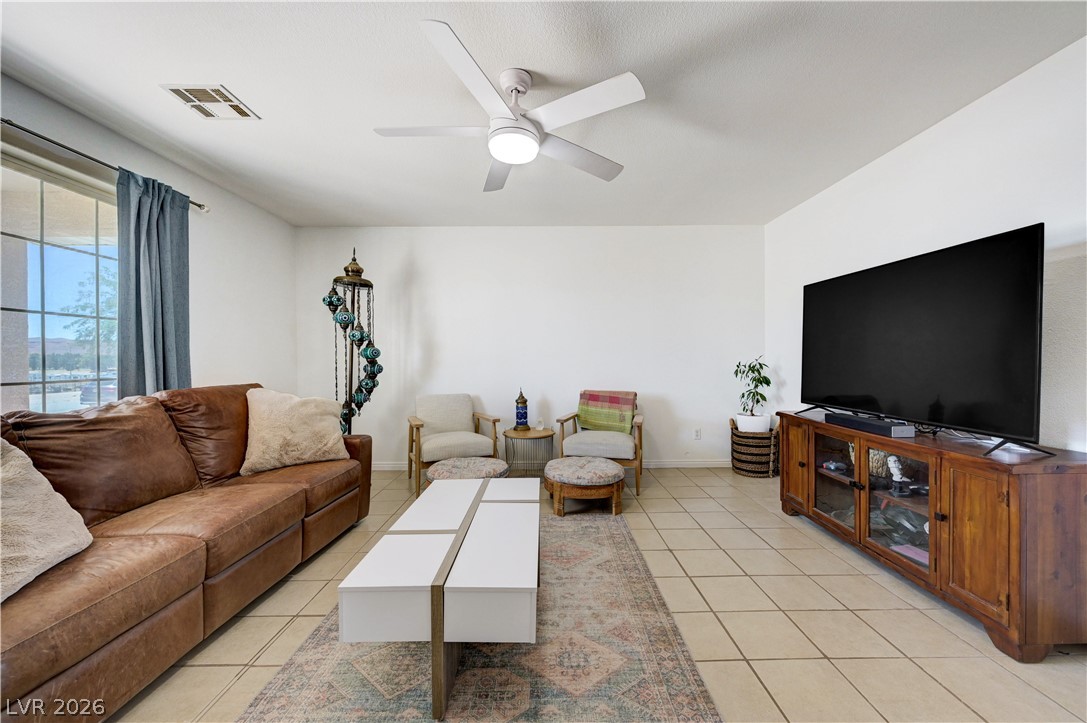 1272 Liston Avenue Logandale, NV 89021 - Photo 12 of 61 A well-lit living area showcases ceramic tile flooring and a ceiling fan, offering a comfortable gathering space.