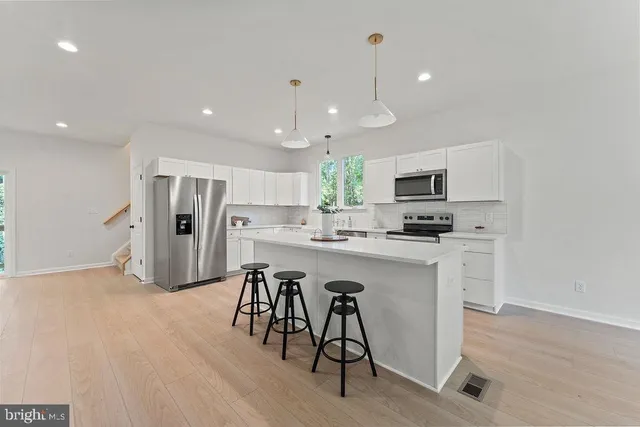 a kitchen with white cabinets and dining table