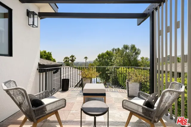 a balcony with chairs and a potted plant