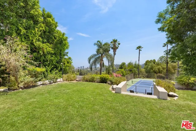 a backyard of a house with table and chairs plants and large trees