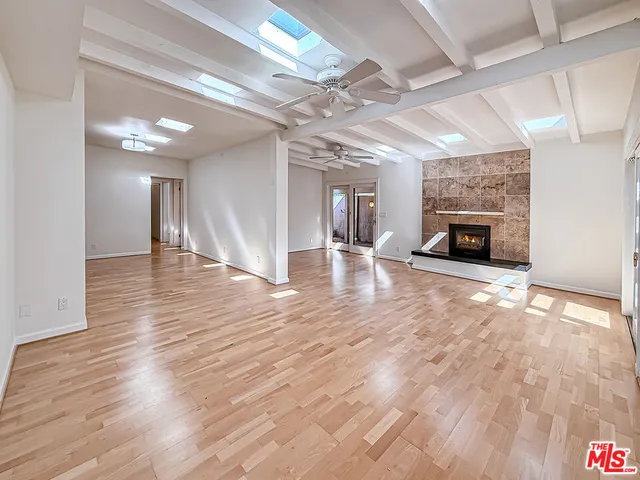 a view of an empty room with wooden floor fireplace and a window