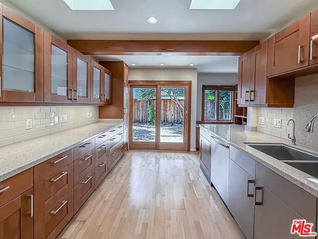 a kitchen with granite countertop wooden cabinets a sink and wooden floors
