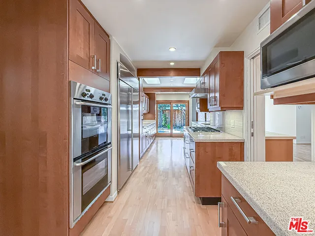 a kitchen with stainless steel appliances granite countertop a refrigerator a stove and a wooden floors