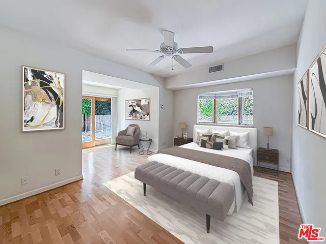 a bedroom with a large bed couch and two windows