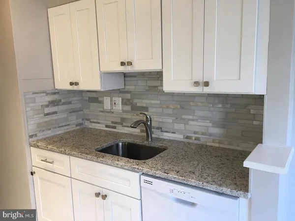 a kitchen with granite countertop white cabinets and a sink