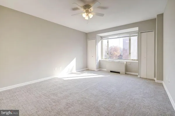 an empty room with chandelier fan and windows