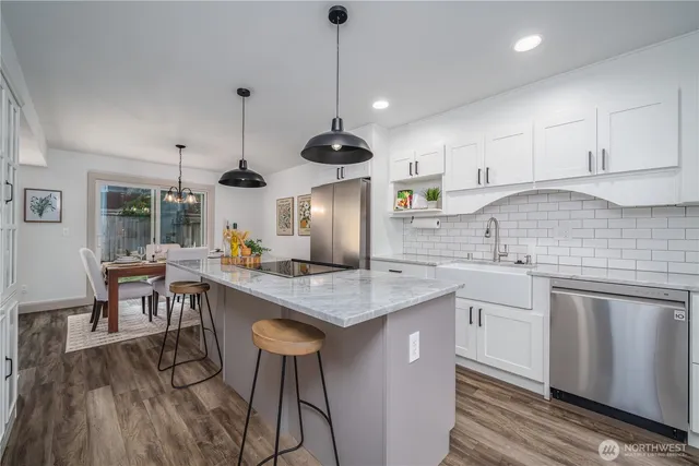 a kitchen with stainless steel appliances granite countertop a sink a stove a refrigerator and island with wooden floor