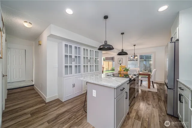 a kitchen with stainless steel appliances granite countertop a stove oven and a wooden floors