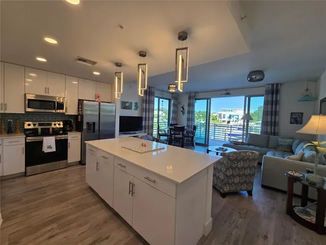 a large kitchen with kitchen island a stove a sink a center island and wooden floor