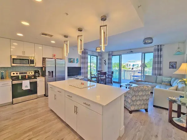 a large kitchen with kitchen island a stove a sink a center island and wooden floor