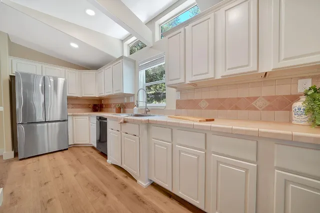 a kitchen with white cabinets white stainless steel appliances and center island